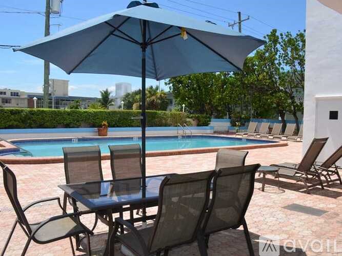 A blue umbrella is on a table with chairs around it.