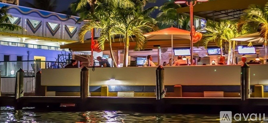 A bar is lit up at night with people sitting at tables.