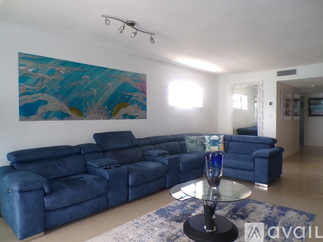 A blue sofa set in a room with a painting on the wall.