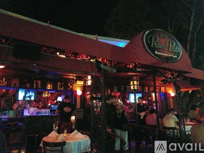 A restaurant with a red awning and people sitting at tables.
