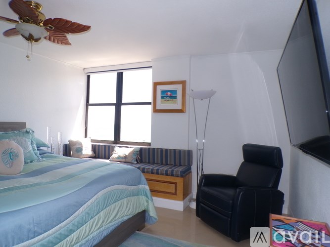 A bedroom with a bed, chair, and a window.