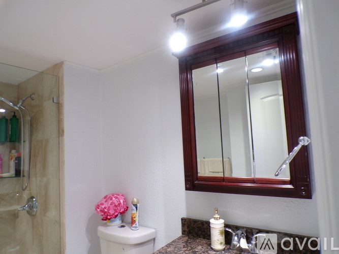 A bathroom with a toilet, sink, mirror, and a shower.