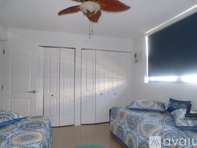 A bedroom with a bed, a ceiling fan, and a window with blinds.