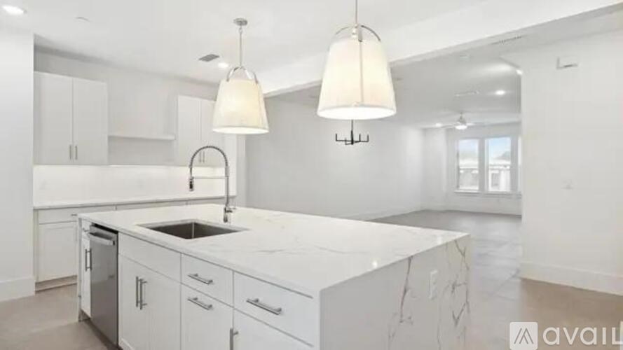 A modern kitchen with white cabinets and a marble countertop.