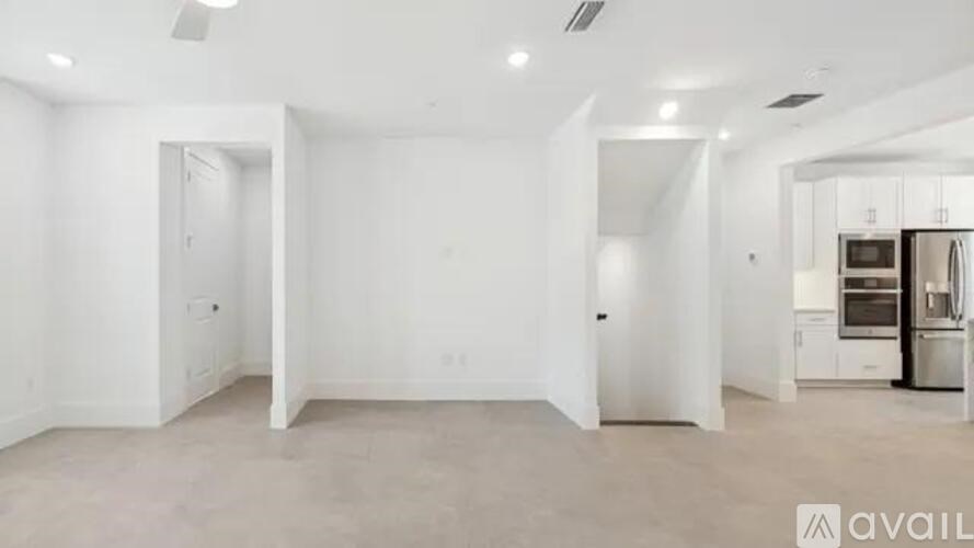 A spacious, empty room with a kitchen area in the background.