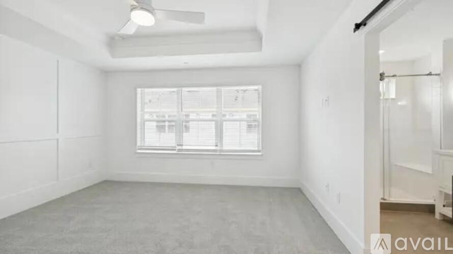 A spacious empty room with a window and a fan on the ceiling.