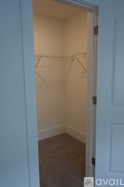 A white door is open to a room with a carpeted floor and a white wall.