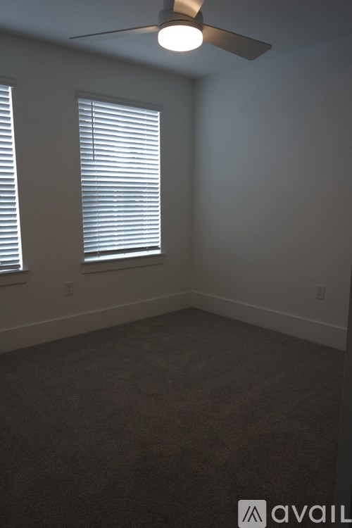 A room with a fan and two windows.