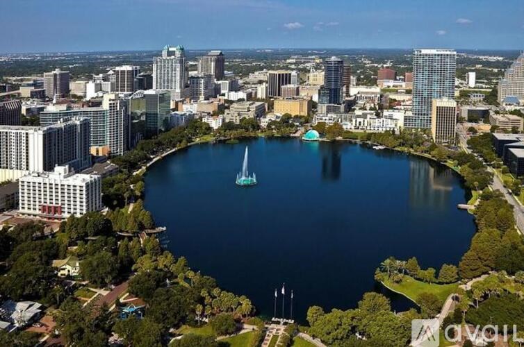A cityscape with a large body of water in the center and a sailboat in the water.
