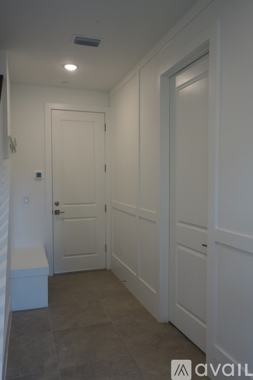 A hallway with white doors and a bench.