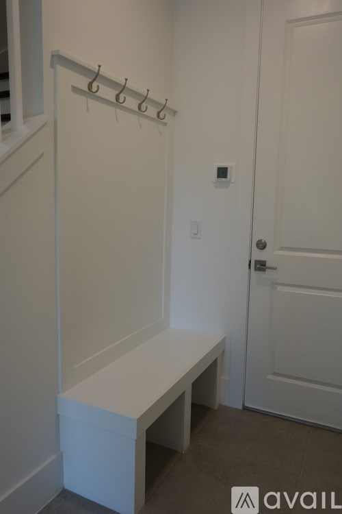 A white bathroom with a towel rack and a bench.