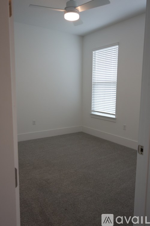 A room with a carpeted floor and a window with blinds.