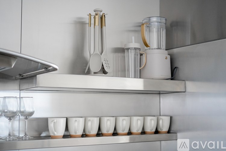 A kitchen with a shelf holding cups and a blender on the counter.
