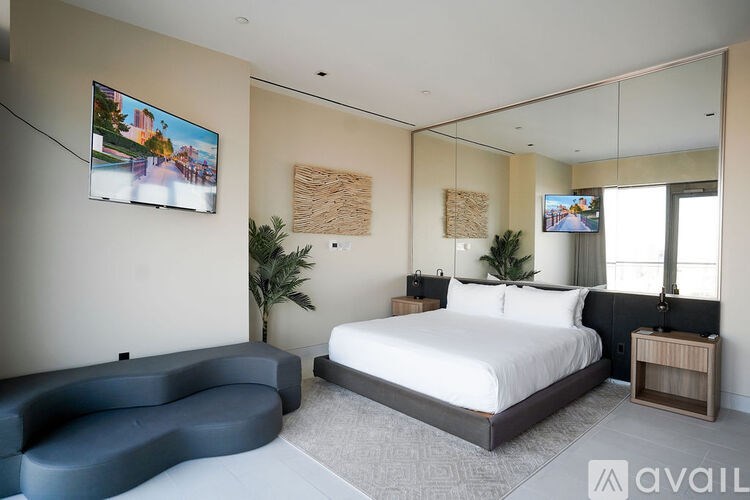 A living room with a grey couch, a coffee table with a chess set on it, and a large window with a view of the city.