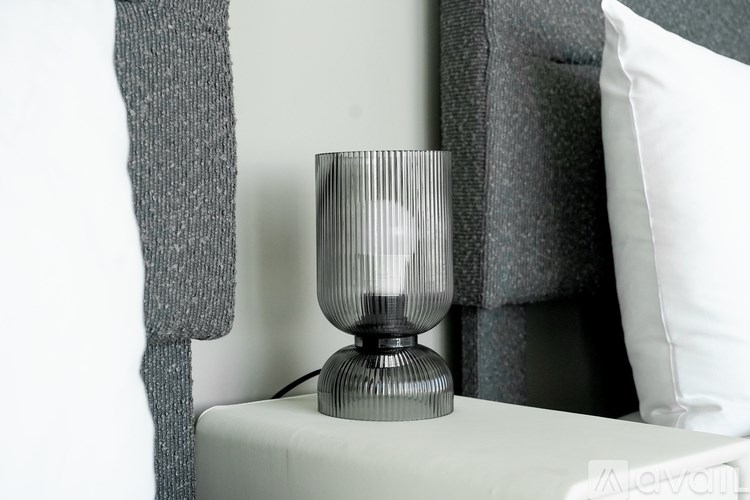 A grey table lamp sits on a white table.