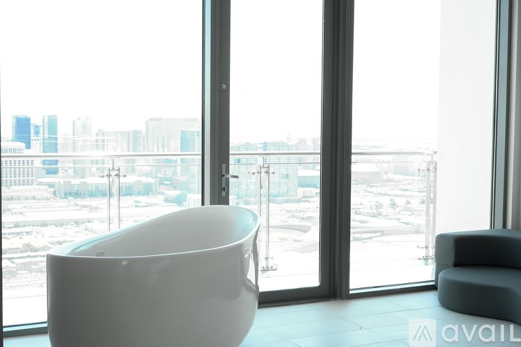 A white bathtub is in a room with a view of a city.