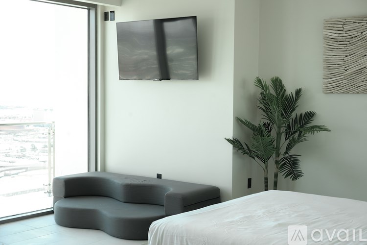A modern bedroom with a large bed and a grey sofa.