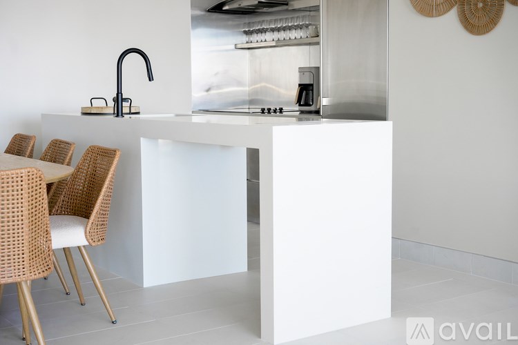 A modern kitchen with a white island and chairs.