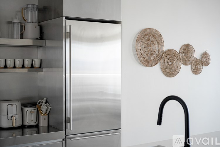 A modern kitchen with a stainless steel refrigerator and a wall-mounted rack with cups and a toaster.