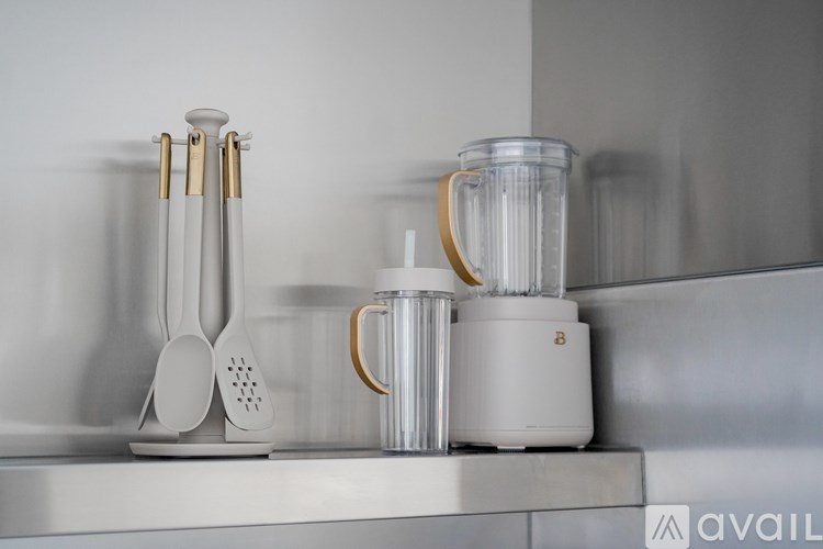 A kitchen counter with a blender, a juicer, and a grater on it.