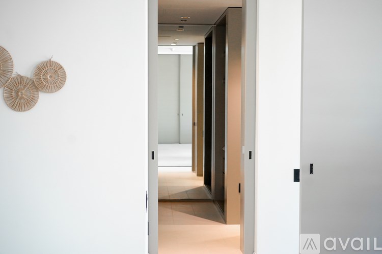 A hallway with a door on the right and a wall hanging on the left.