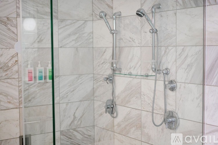 A shower with a glass door and a marble wall.