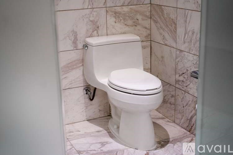 A white toilet in a marble tiled bathroom.