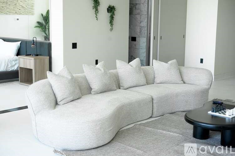 A white couch with seven pillows sits in a living room.