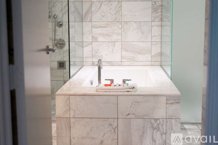 A bathroom with a marble countertop and a glass shower door.