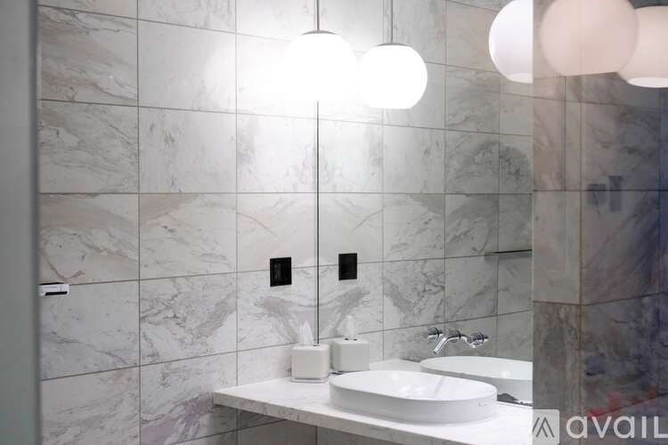 A bathroom with a marble wall and a white sink.