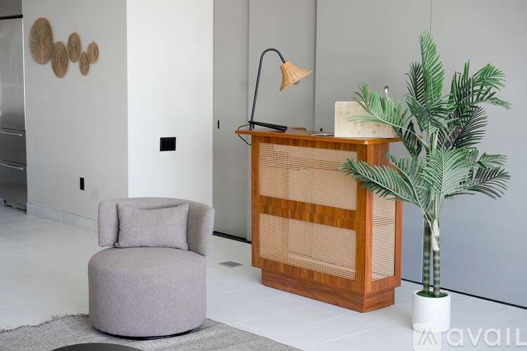 A grey chair sits in front of a wooden cabinet with a potted plant to the side.