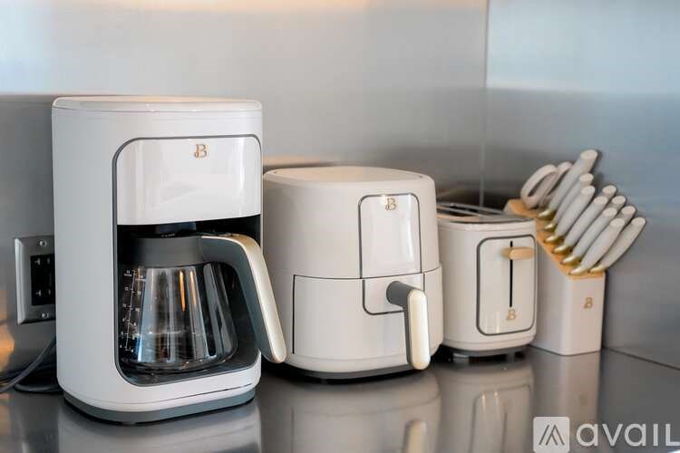 A white coffee maker and a white coffee pot are on a counter.