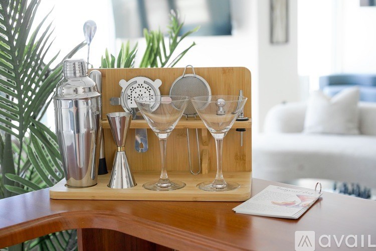A wooden tray with a set of silverware and glasses on it.