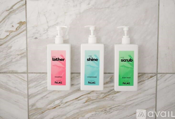 Three bottles of Palms shampoo, conditioner and body wash on a marble surface.