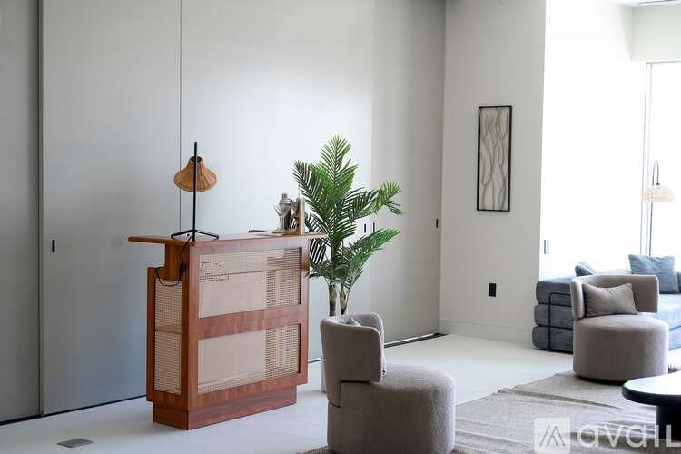 A room with a wooden cabinet, a potted plant, and a grey sofa.