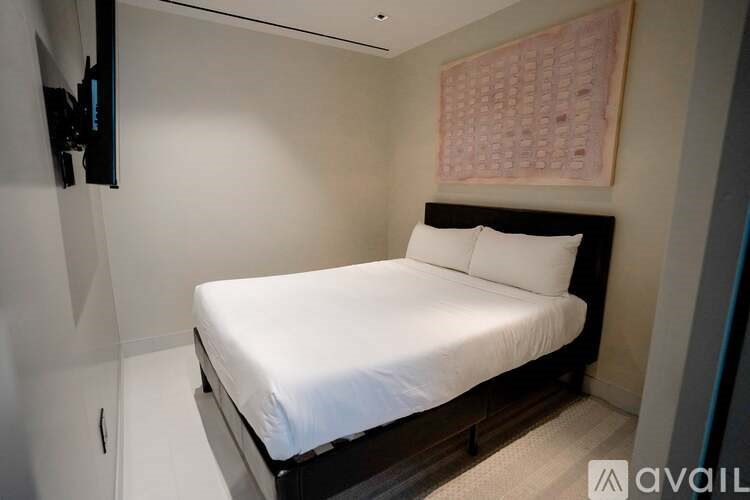 A bed with white bedding sits in a room with a wall hanging and a television.