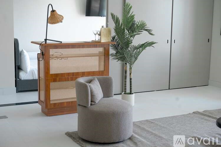 A room with a chair, a table, and a plant.