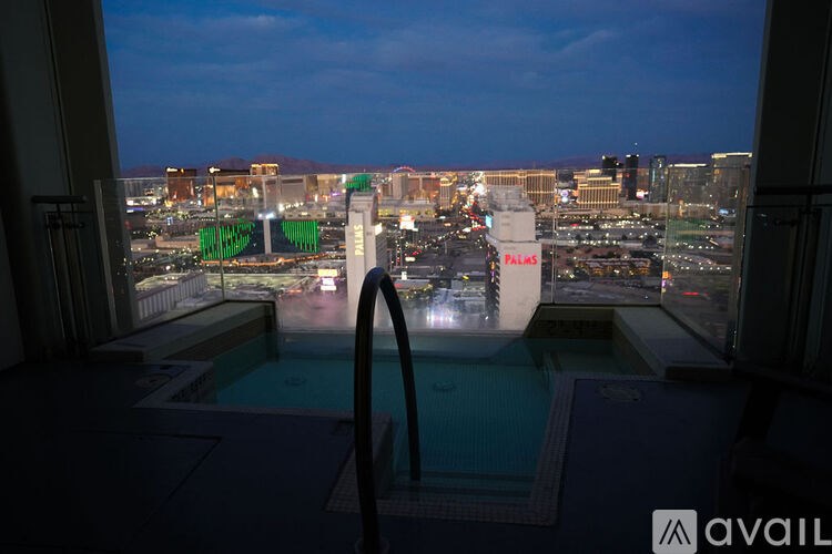 A view of a cityscape from a window overlooking a pool at dusk.
