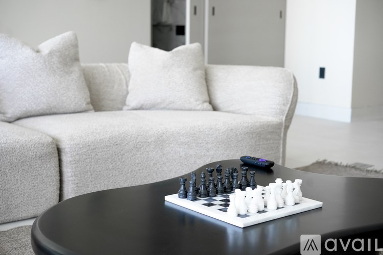A chess board with pieces on it sits on a table in front of a couch.