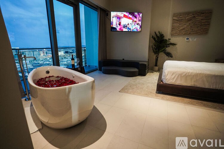 A room with a large tub filled with red flowers and a bed.