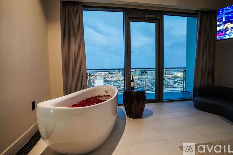 A bathroom with a tub full of rose petals and a view of the ocean through the sliding glass doors.