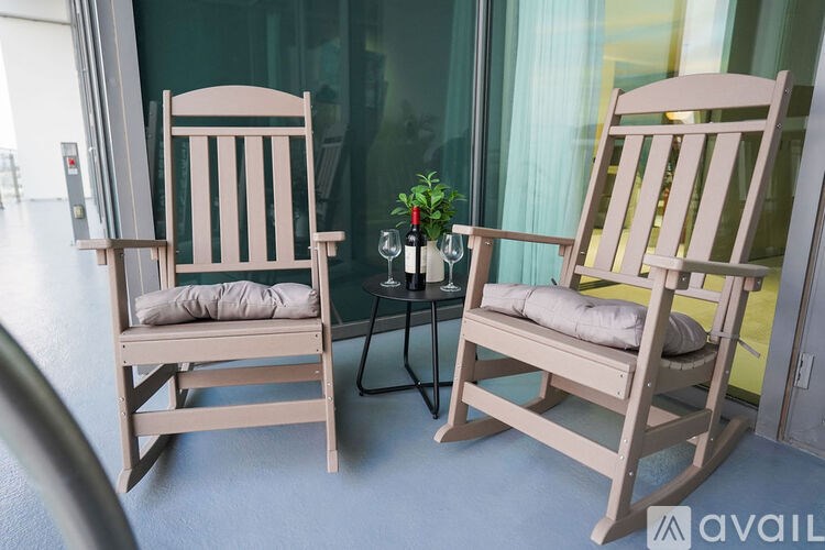Two wooden chairs with cushions are placed in front of a glass wall.