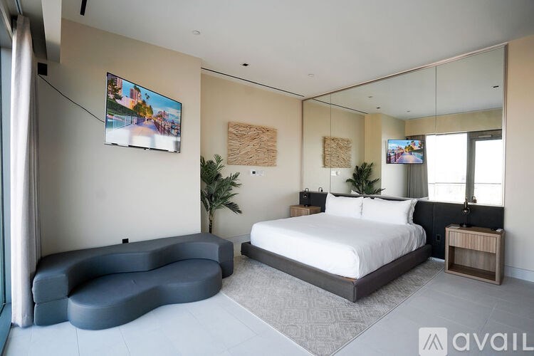 A modern bedroom with a large bed and a blue chaise lounge.