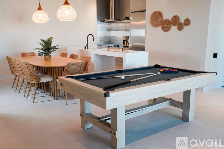 A pool table is in the middle of a room with a dining table and chairs.
