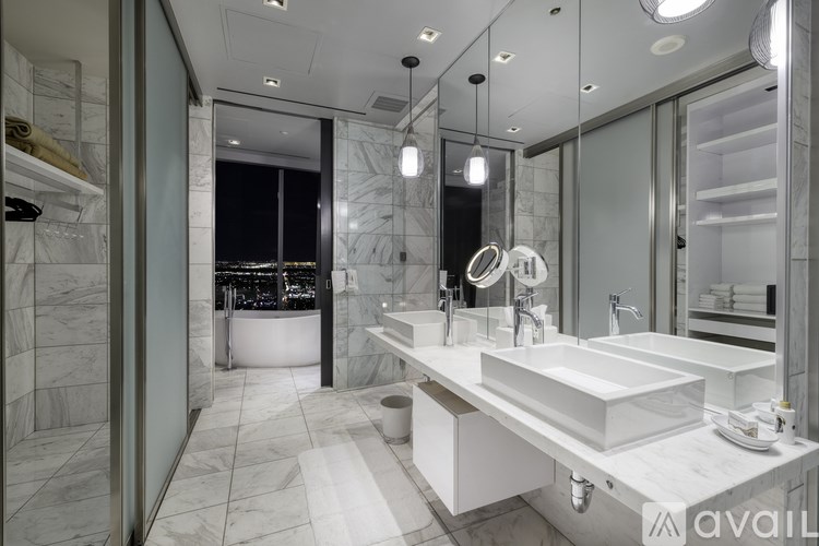 A modern bathroom with a large mirror and a view of the city.