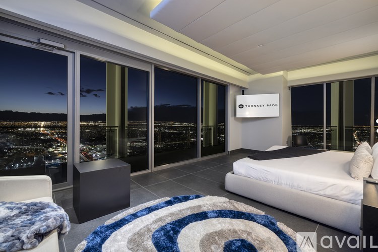A bedroom with a large bed and a view of the city at night.
