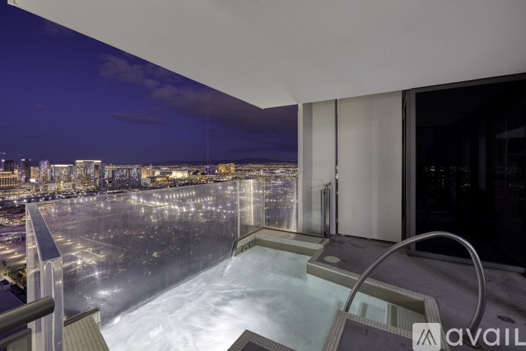 A hot tub on a balcony overlooking a city at night.