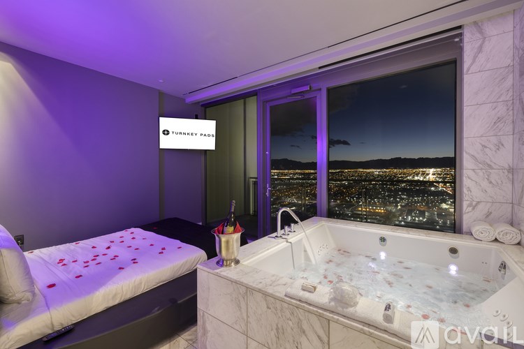 A room with a jacuzzi tub and a bed with a city view.