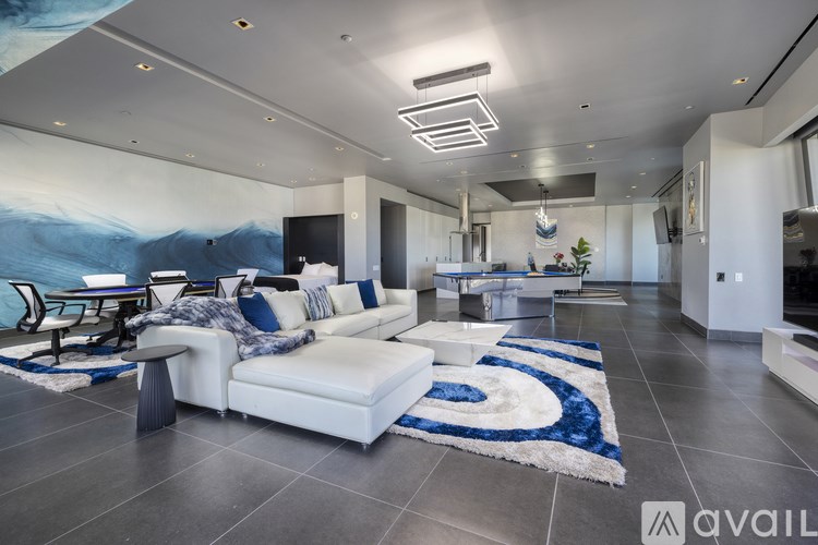 A modern living room with a white sofa and a blue rug.