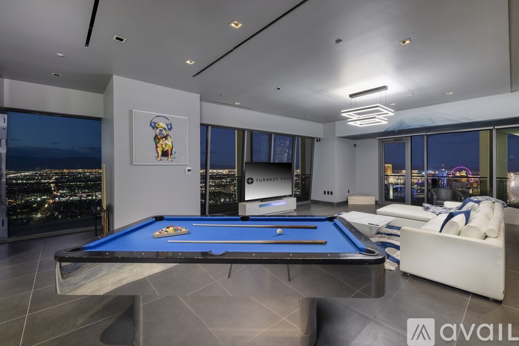 A pool table in a room with a view of the city at night.